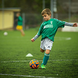 Photo d'un enfant en tenue de football tapant dans le ballon
